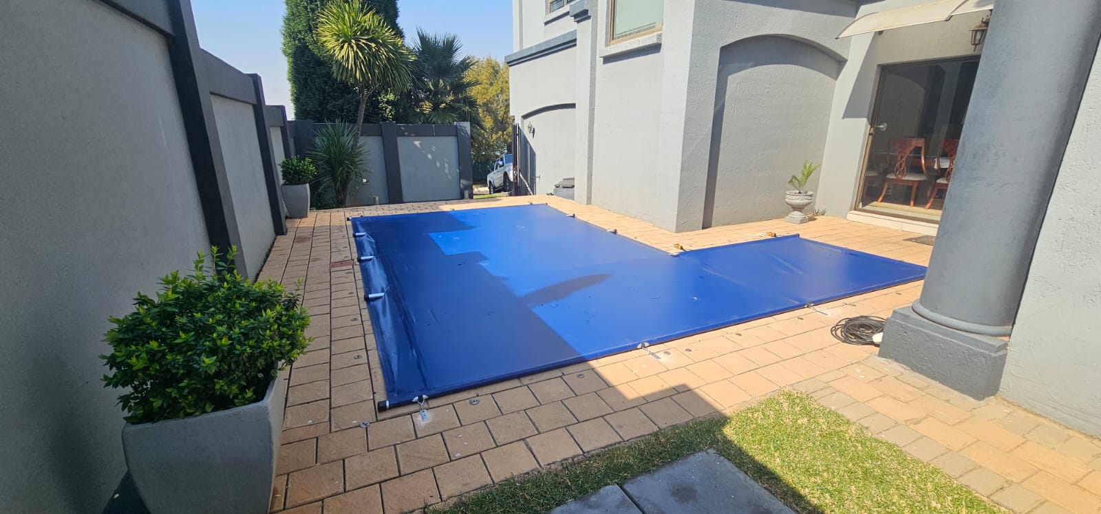 Blue safety pool cover fitted over an L-shaped pool