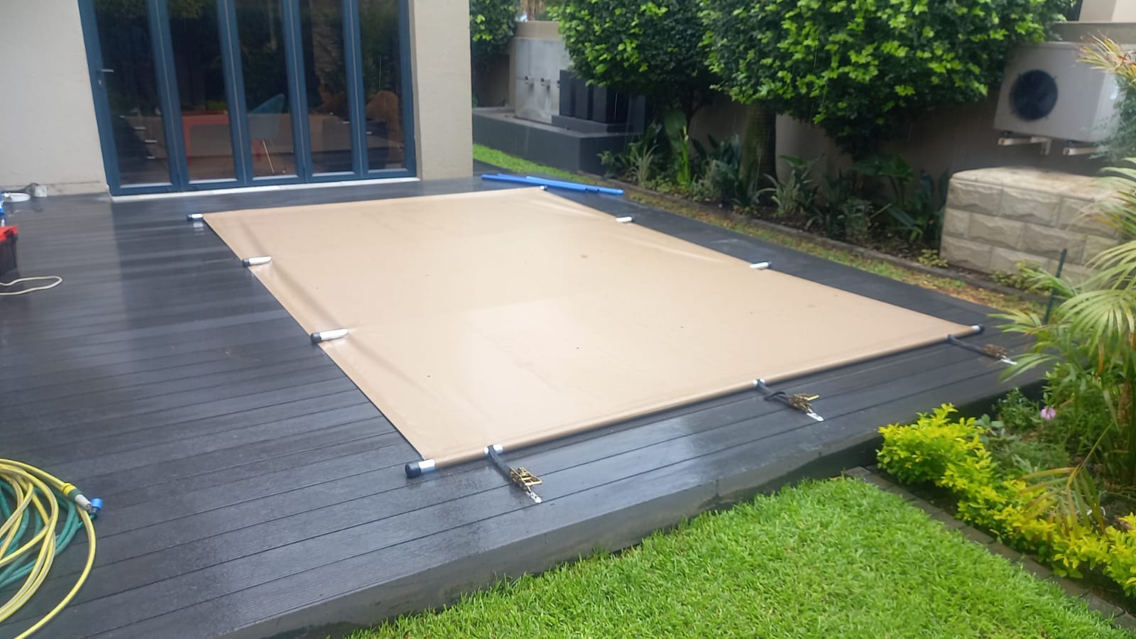 Tan pool cover fitted to a timber deck pool