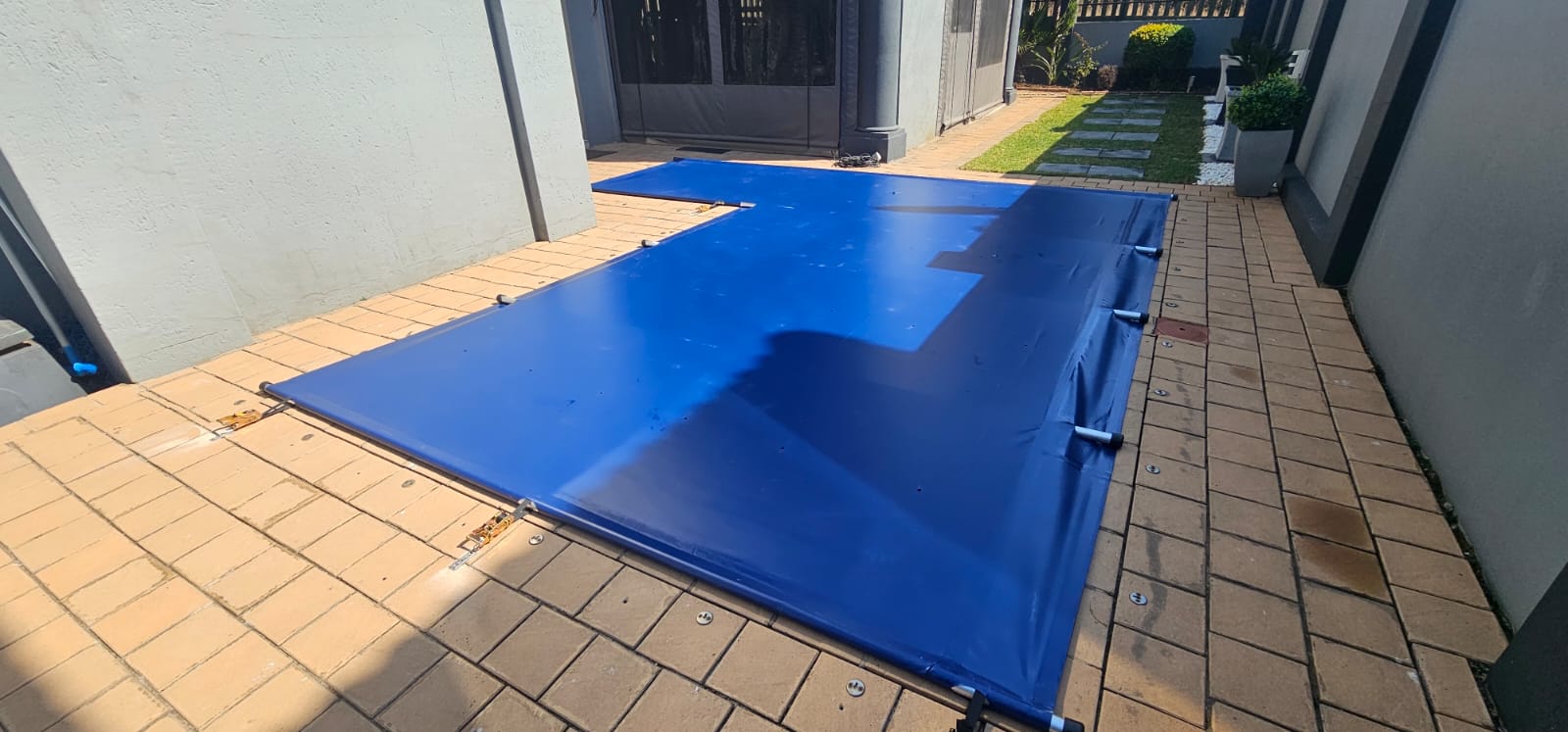 Blue pool cover secured with ratchet straps
